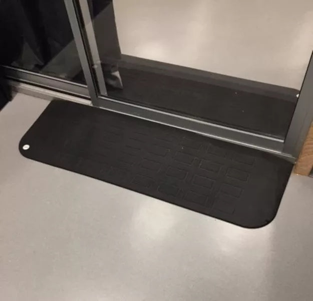 Black mat on a floor next to a glass door, EZEdge™ Wheelchair Ramps